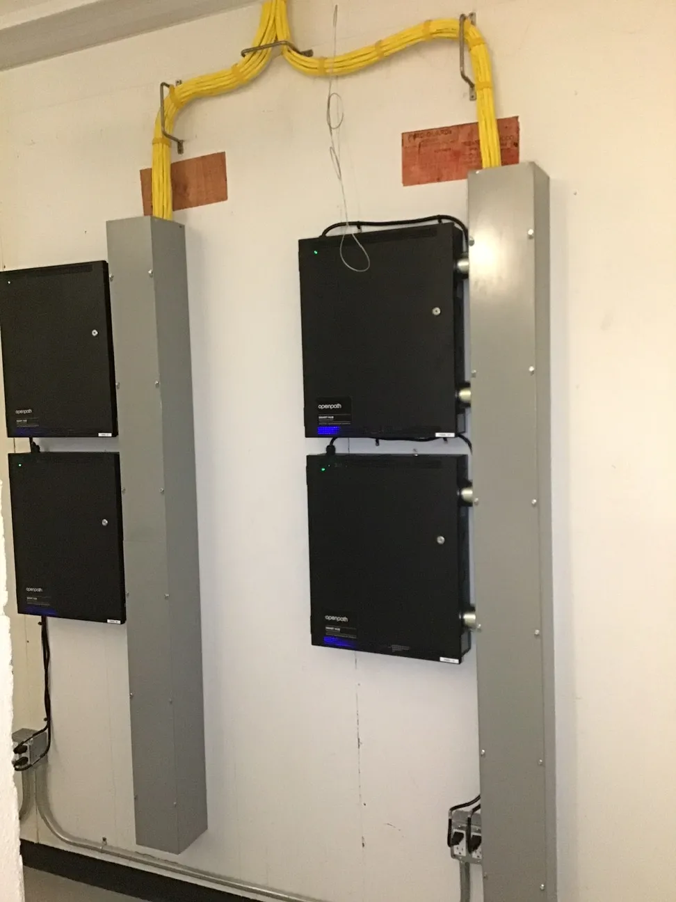 Four Openpath smart hub access control panels mounted on wall channel with network cabling routed overhead