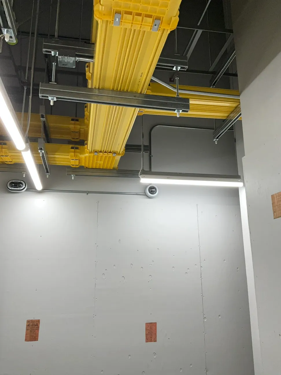 Overhead fiber raceway and cable tray with dome cameras mounted along the wall below