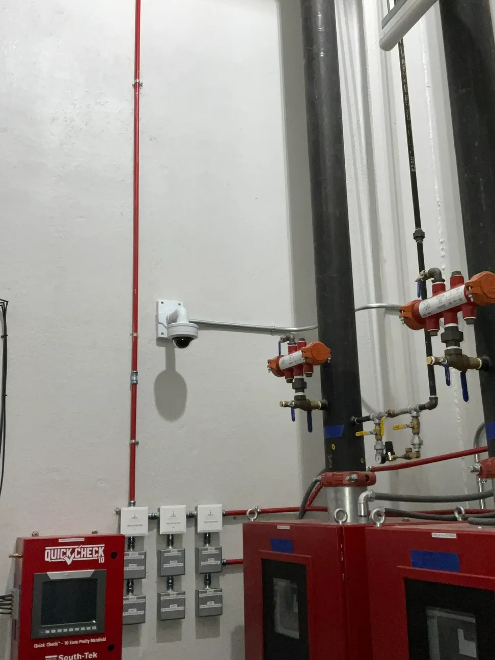 Dome camera on a wall mount covering a fire suppression manifold in a mechanical room